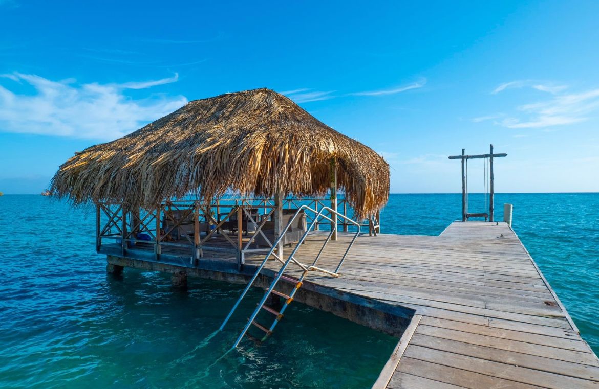 Muelle de madera con palapa sobre aguas cristalinas