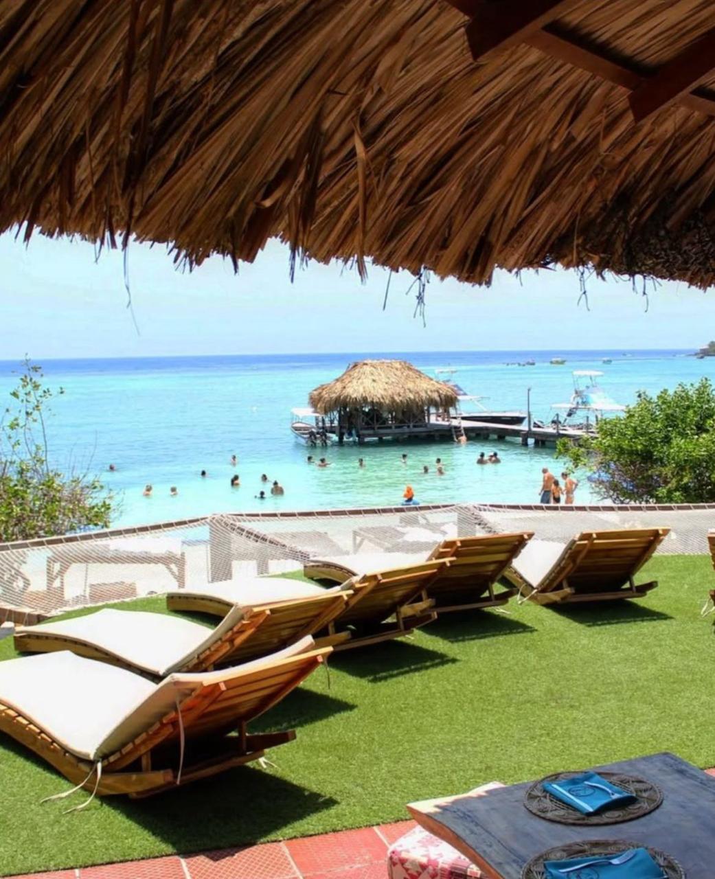 Camas sobre grama con palapa frente al mar