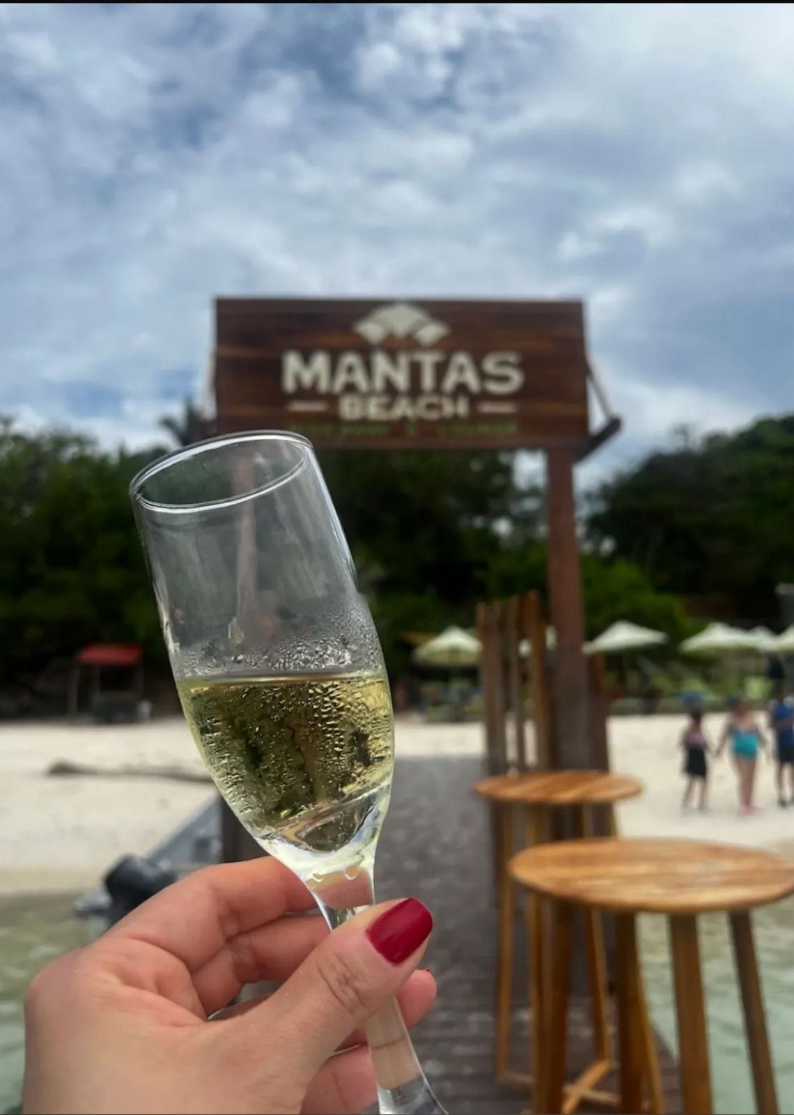 Brindis con champaña frente al letrero Mantas Beach