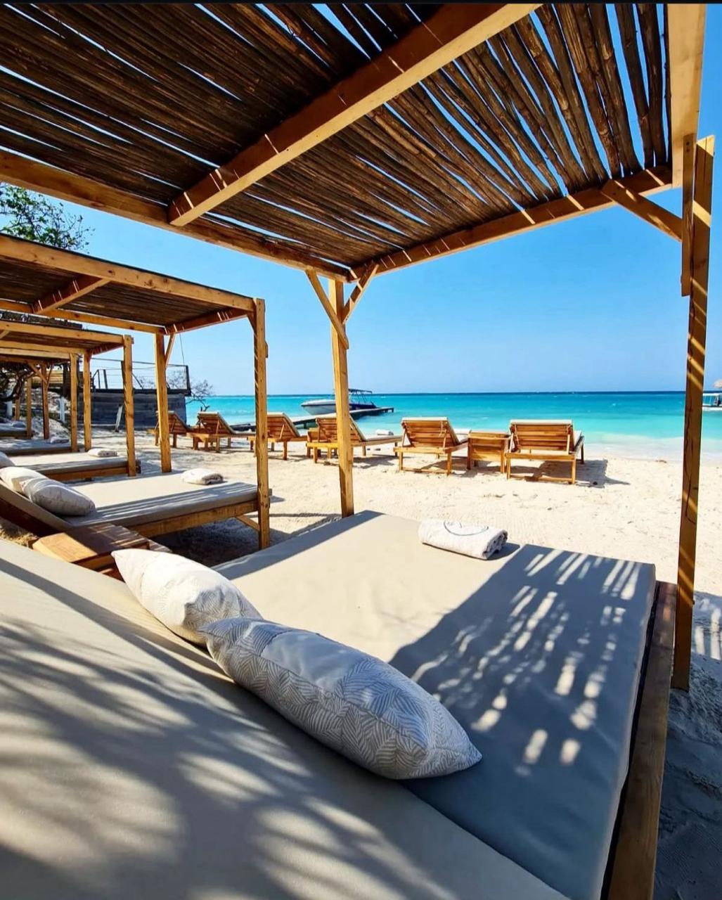 Camas balinesas bajo pérgola en la arena