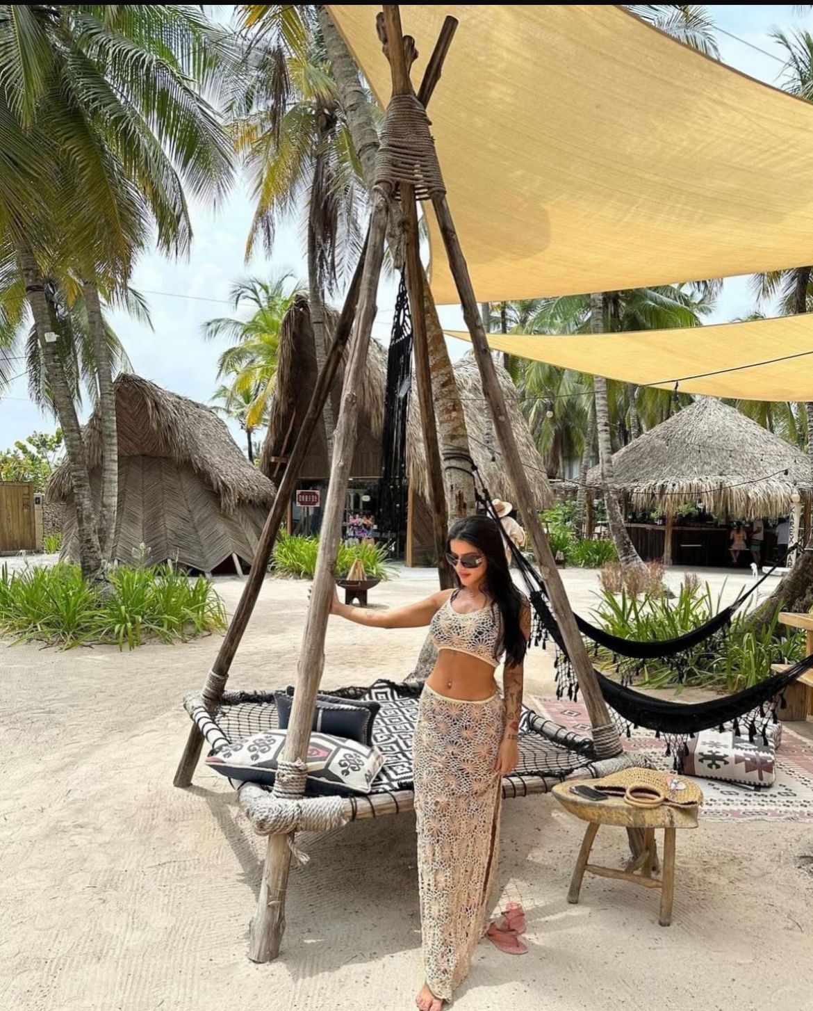 Cama tipi con vela de sombra en la arena