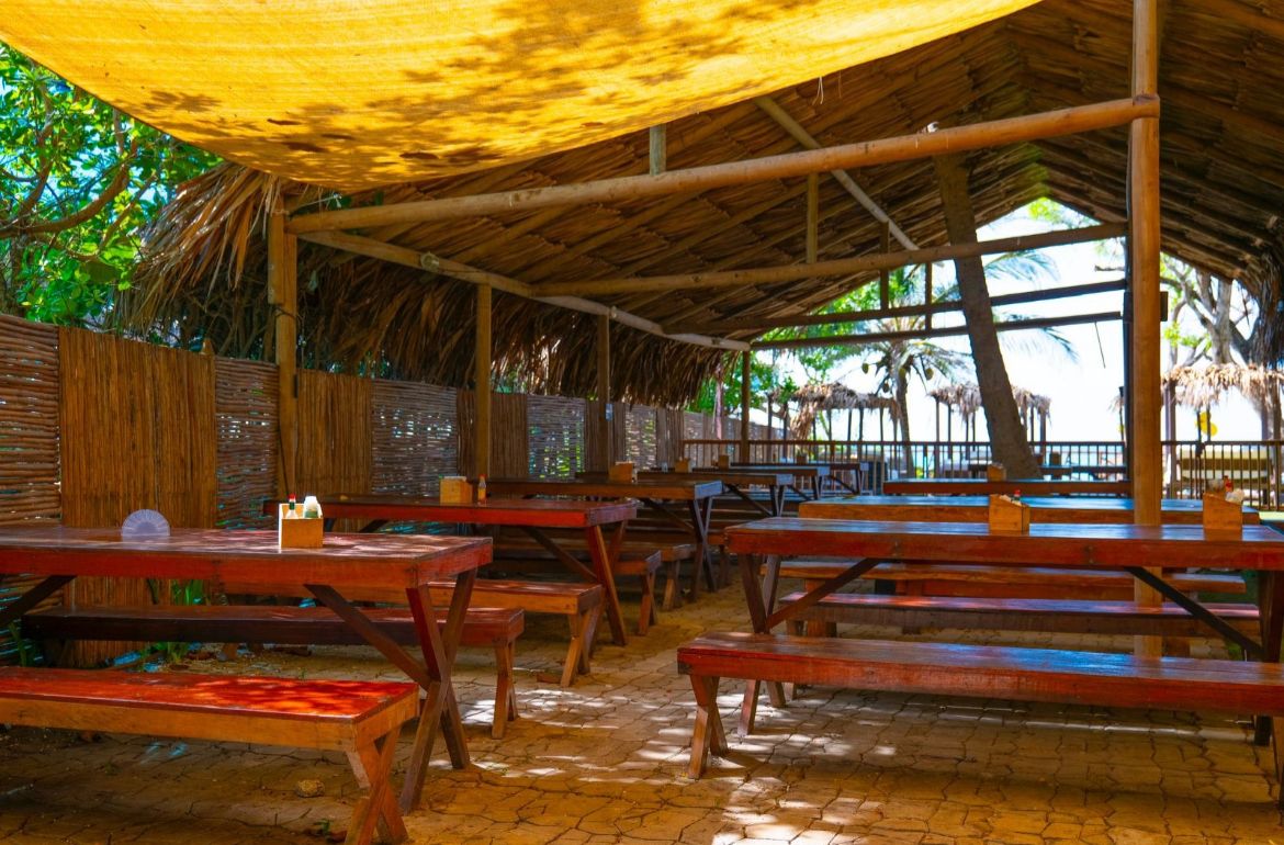 Comedor rústico con techos de palma y mesas de madera