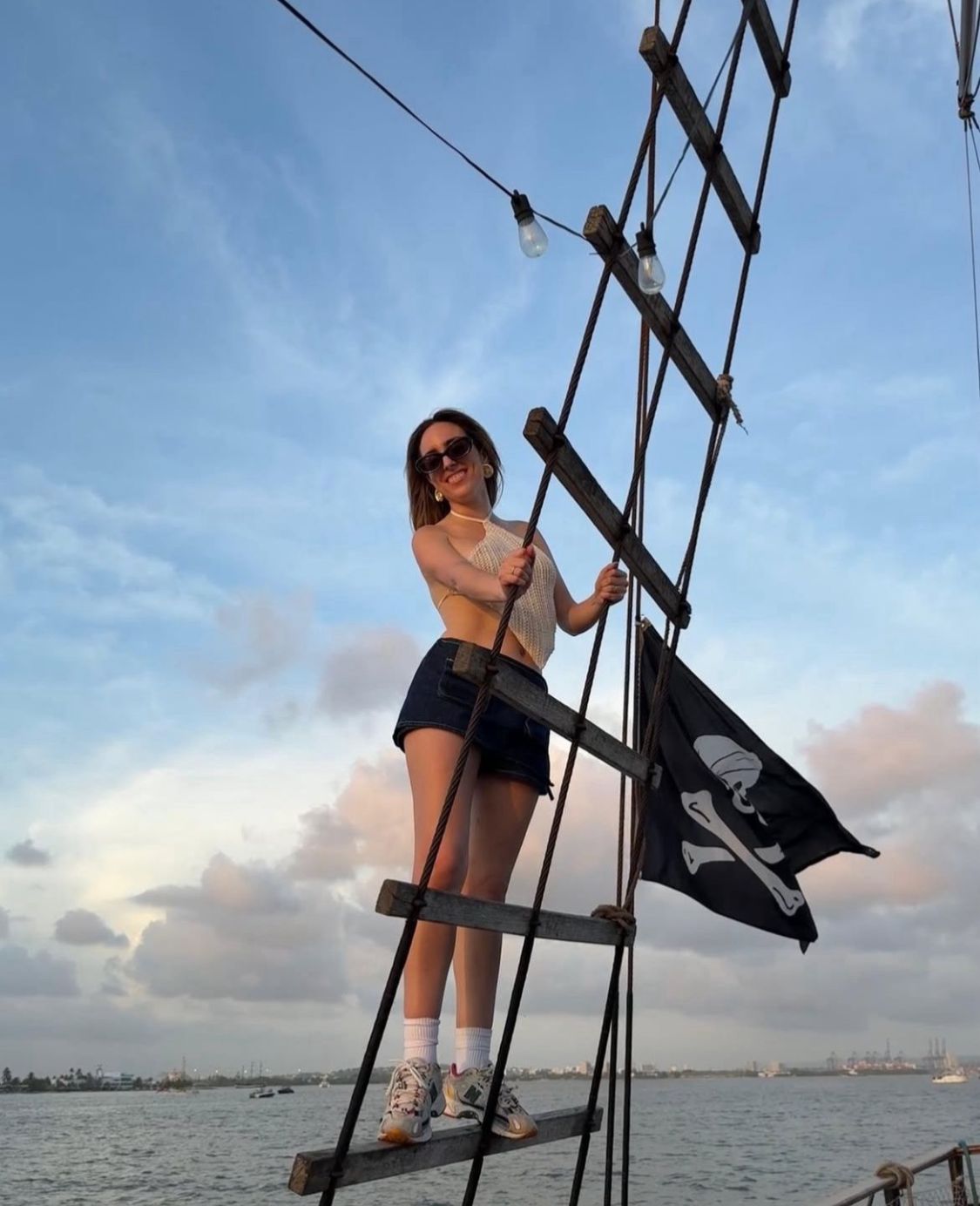 Pasajera junto a la bandera pirata al atardecer